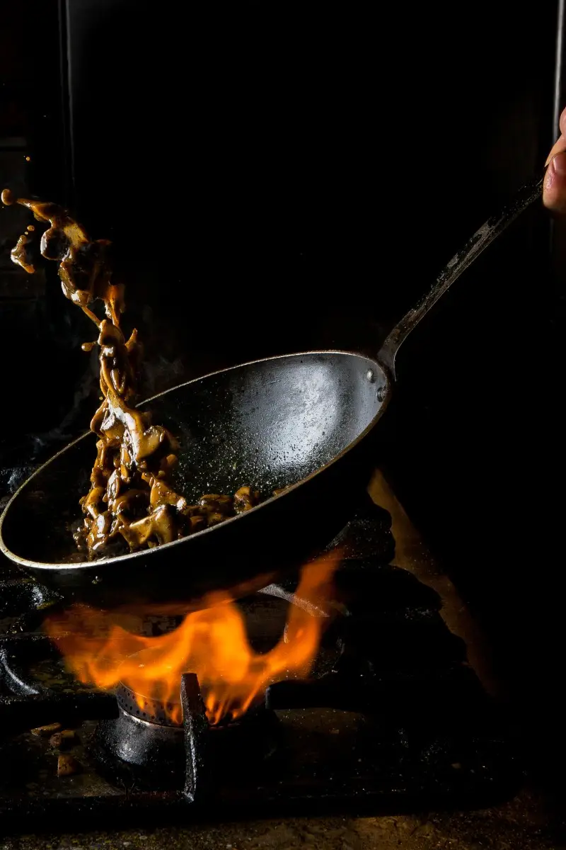 side-view-mushroom-frying-with-gas-stove-fire-human-hand-pan (2)
